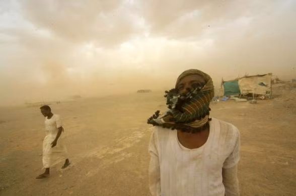 Công nhân mỏ vàng đi bộ đến nơi trú ẩn của họ trong một cơn bão cát tại Al-Ibedia tại bang River Nile, Sudan.
