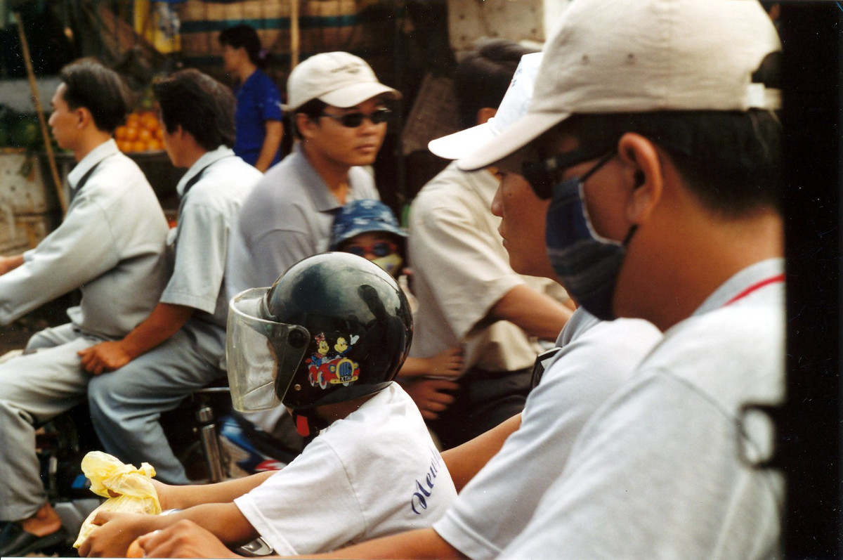 Em bé đội mũ bảo hiểm khi ngồi trước xe máy của bố.