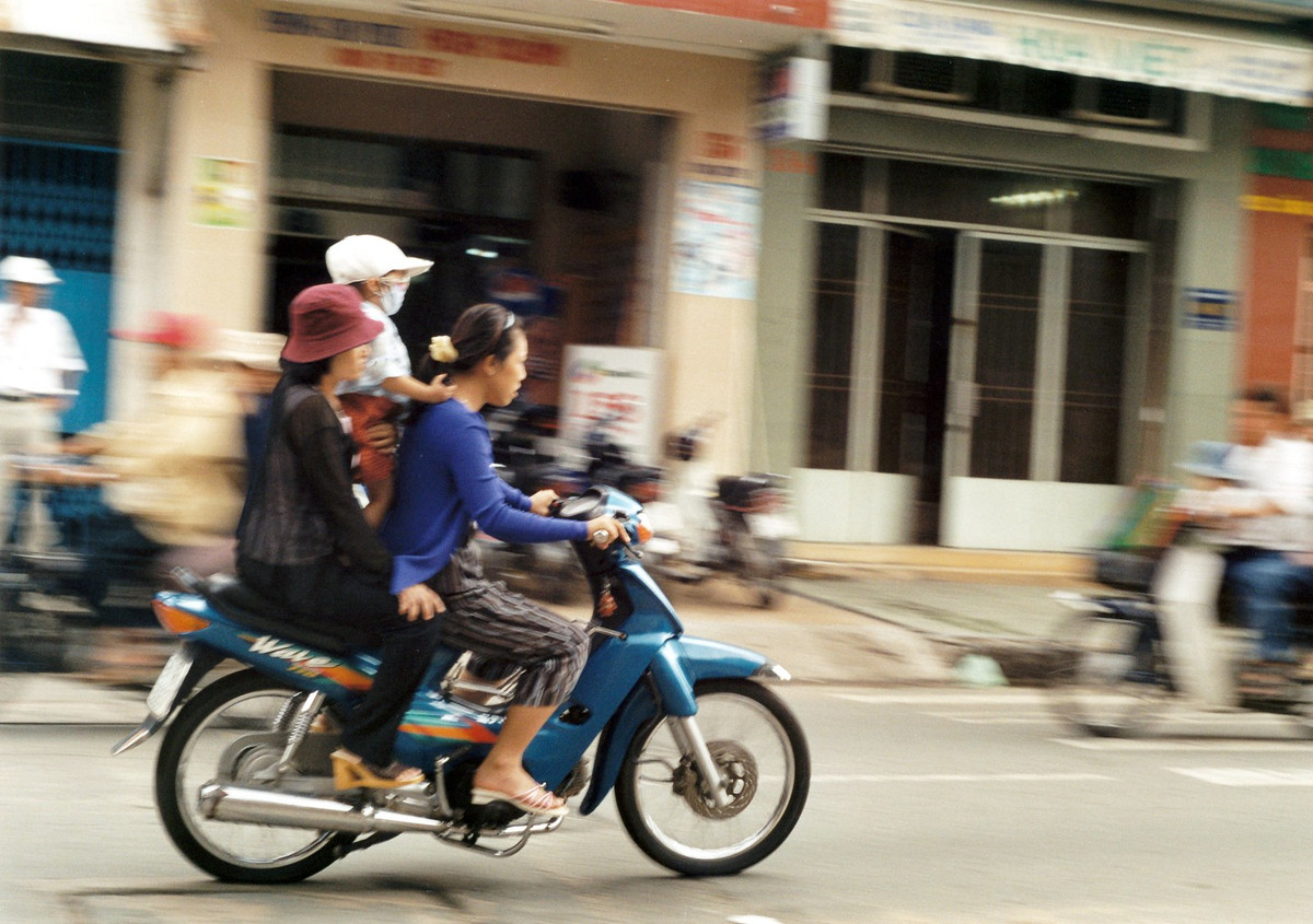 Hai người phụ nữ và em bé trên chiếc xe Wave.