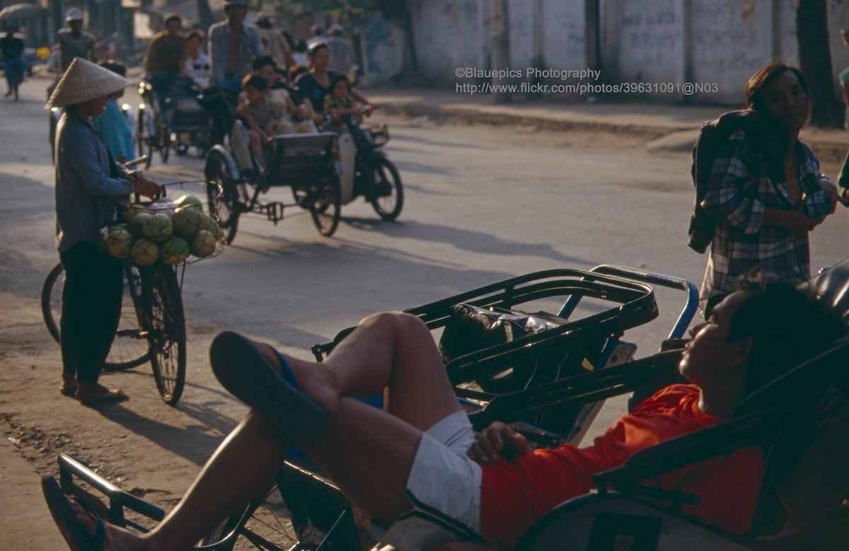 Giấc ngủ giữa dòng người qua lại trên phố đông.