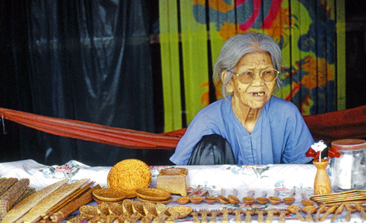 Cụ bà ngồi bán các món đồ mỹ nghệ làm bằng gỗ dừa.