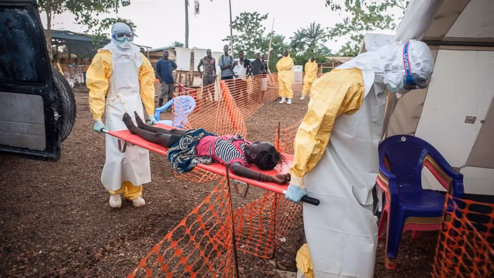Người thân đứng từ xa dõi theo em bé bị nhiễm Ebola được các nhân viên y tế đưa vào vùng cách ly.