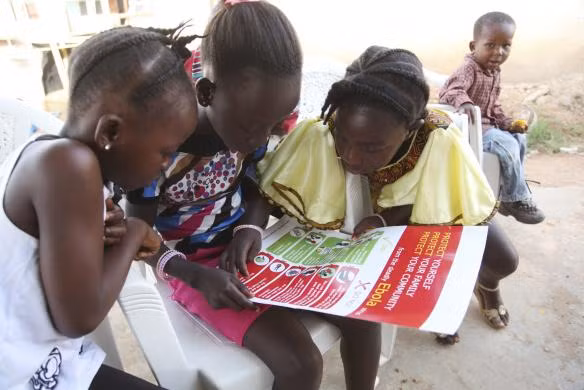 Những đứa trẻ chăm chú đọc tin tức về dịch Ebola được phân phối bởi UNICEF tại Voinjama, Lofa County, Liberia.