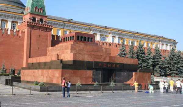 Tấm nắp kính nguyên khối hình bậc thang nằm phía trên cỗ quan quách như treo lơ lửng trên các thành bằng kính trong suốt. Nó được đỡ bởi bốn cây cột kim loại ở 4 góc, thực tế hầu như không nhận thấy. Bậc dưới cùng của tấm được phủ bằng ngọc bích màu đỏ nhạt của vùng Orsk. Hai bên sườn của cỗ quan quách là hai lá cờ: một lá quân kỳ và một lá cờ búa liềm. Hai lá cờ được thả rủ xuống lấp lánh ánh vàng, thực tế chúng màu đồng nhưng do cách chiếu sáng đặc biệt nên cảm giác bóng sáng hơn. Ảnh: Lăng Lenin trên Quảng trường Đỏ.