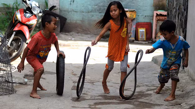 Những đứa trẻ sống gần kênh Cầu Mé (phường 3, quận 11, TP.HCM) vui đùa cùng những chiếc lốp xe cũ - Ảnh: Nguyễn Quang. 