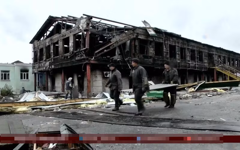 Các dân quân khiêng các thi thể bị chôn vùi dưới hố tập thể lên để tiến hành điều tra.