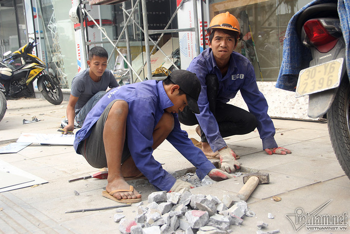 Trong những ngày này, dọc 2 bên tuyến đường Nguyễn Trãi, đơn vị thi công cử công nhân sửa lại, thay mới những viên đá hư hỏng. Chưa đầy 1 tiếng làm việc, công nhân đã phải sửa chữa ít nhất 4-5 vị trí trên tuyến đường, dọc 2 bên vỉa hè nhiều đá được xếp sẵn để chờ thay thế. Ảnh: Công nhân cạo bỏ lớp xi vữa cũ.