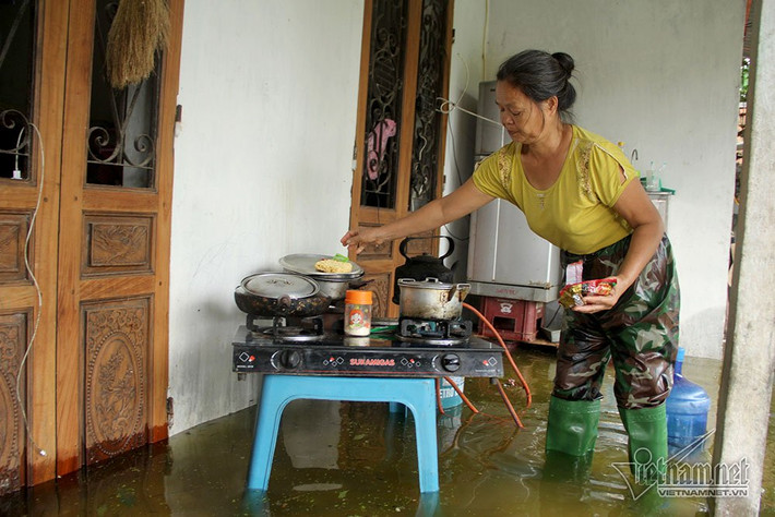Bà Duyên bì bõm nấu ăn trong nước lũ