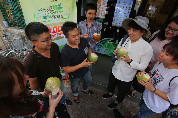 Các bạn trẻ thích thú giải nhiệt với những trái dừa được tặng miễn phí từ máy bán dừa tự động trên đường Hồ Tùng Mậu, quận 1.