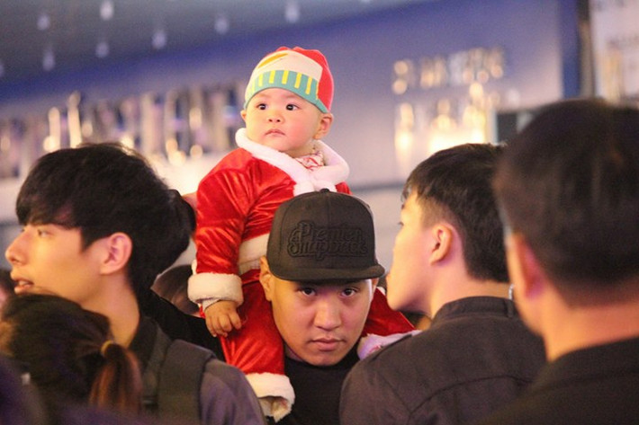 Bé trai được cha mẹ khoác bộ đồ ông già Noel đi chơi Giáng sinh.