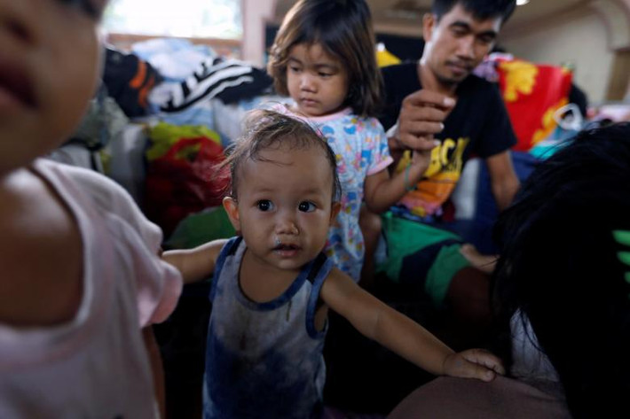 Một em bé chạy loạn cùng cha mẹ. Ảnh: REUTERS