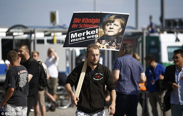 Một người biểu tình vác biểu ngữ “Merkel phải từ chức”.