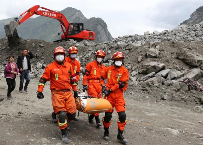 Nhân viên cứu hộ khiêng một thi thể nạn nhân ra khỏi hiện trường vụ lở đất xảy ra vào ngày 24/6. Ảnh: China Daily.