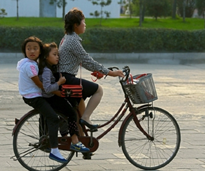 Đưa con đi học. Xe đạp vẫn là phương tiện đi lại khá phổ biến ở CHDCND Triều Tiên.