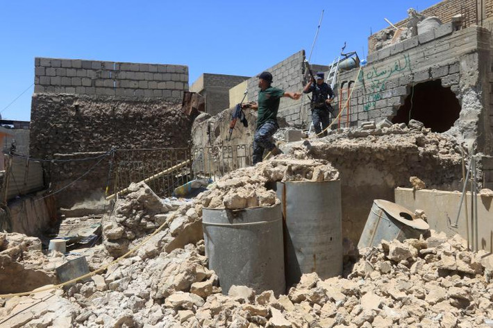 Cảnh sát Iraq đi qua một ngôi nhà đổ nát ở quận Bab al Jadid thuộc khu vực Thành phố cổ Mosul. Ảnh: REUTERS