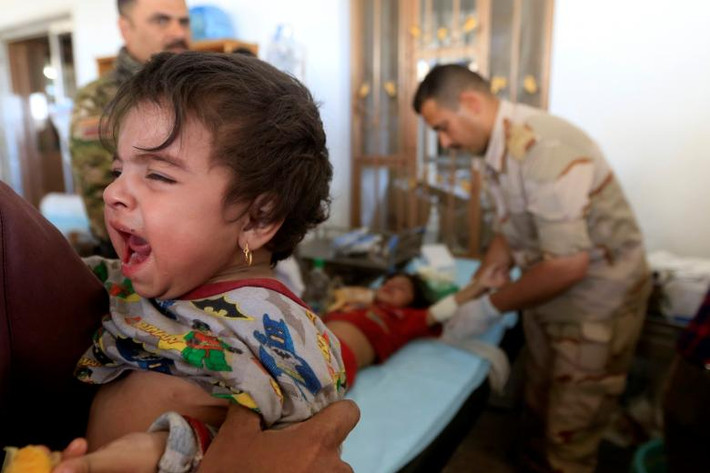 Trẻ em Iraq bị thương trong khi chạy trốn khỏi khu vực do phiến quân IS kiểm soát ở Tây Mosul và đang được băng bó ở bệnh viện dã chiến. Ảnh: REUTERS
