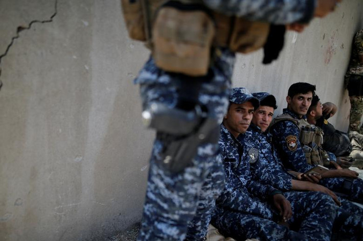 Các thành viên Cảnh sát liên bang Iraq nghỉ ngơi sau bức tường sát trận tuyến Tây Mosul. Ảnh: REUTERS