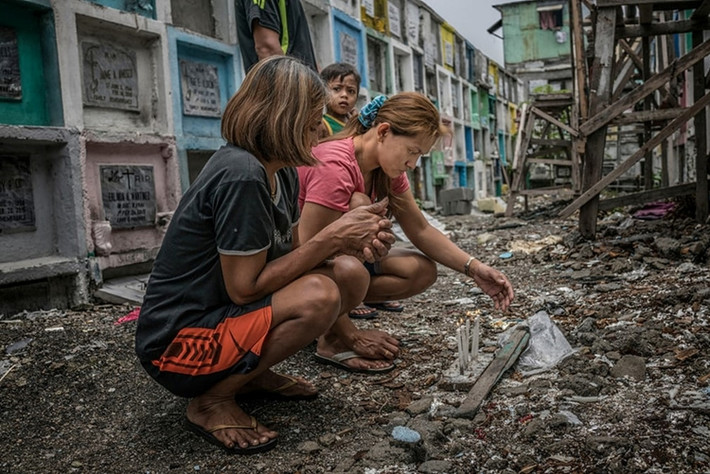 Mary Grace Llimit (áo hồng) thắp nến tại nghĩa trang Công giáo Novatas, Manila. Người em gái 16 tuổi của cô bị giết trong một chiến dịch truy quét của cảnh sát. Ảnh: Guardian.