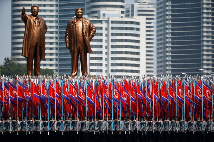 Những sinh viên mặc đồng phục Đại học Triều Tiên mang cờ diễu qua lễ đài. Ảnh: Reuters