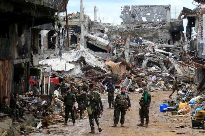Lính chính phủ đứng trước những ngôi nhà bị biến thành đống đổ nát ở thành phố Marawi. Ảnh: REUTERS.