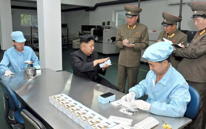 Nhà lãnh đạo Triều Tiên Kim Jong-un dùng thử một chiếc điện thoại di động do nước này tự chế tạo. Ảnh: KCNA