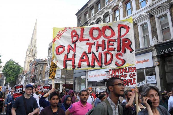 Những người biểu tình giương cao biểu ngữ ở Kensington. Ảnh: REUTERS