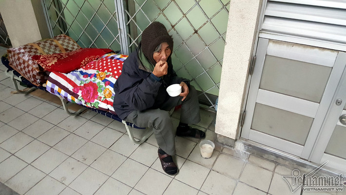 Một cụ già đi nuôi bệnh nhân trầm tư dùng bữa sáng