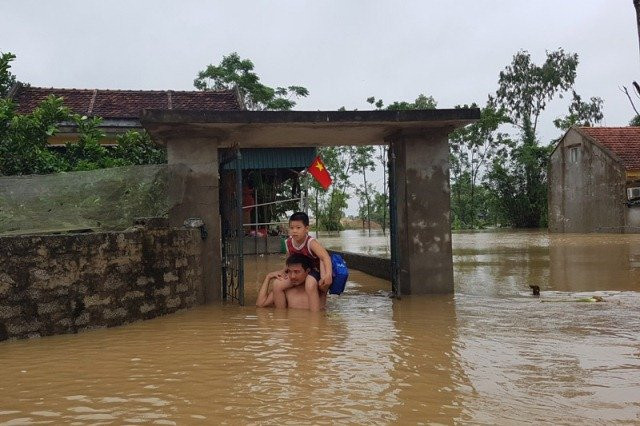 Bố cõng con thoát khỏi nước lũ.