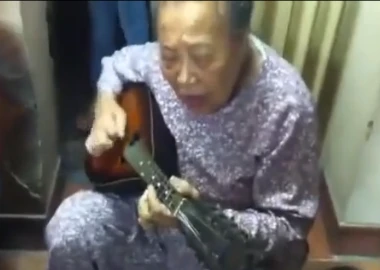 Cụ bà ôm đàn guitar hát một cách hào hùng