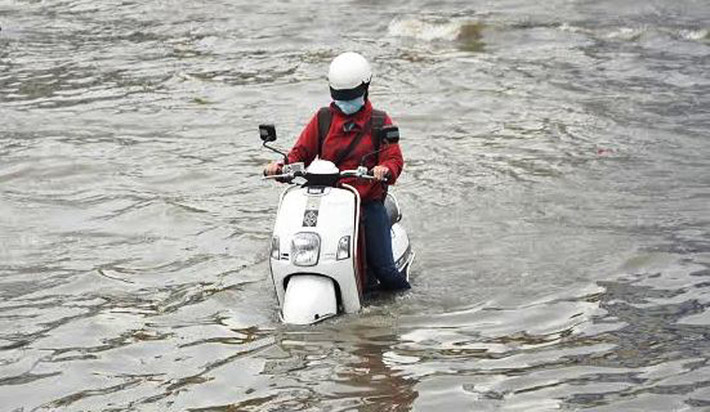 Một cô gái điều khiển xe máy một mình giữa biển nước...