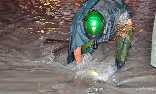 Hình ảnh thượng sĩ công an móc rác giúp đường thoát ngập