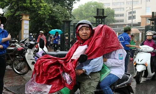 Xúc động cha mẹ đội mưa đưa con đi làm thủ tục dự thi