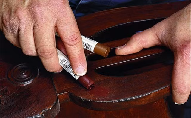 Sử dụng sáp màu hoặc bút màu cùng tone gỗ là giải pháp nhanh gọn cho các vết xước nhẹ trên bề mặt. Bạn chỉ cần chọn sáp hoặc bút màu có tone tương đồng với màu sàn, chà trực tiếp lên vết xước rồi lau sạch phần dư bằng khăn mềm. Cách này giúp che phủ vết trầy và làm sàn trông đều màu hơn.