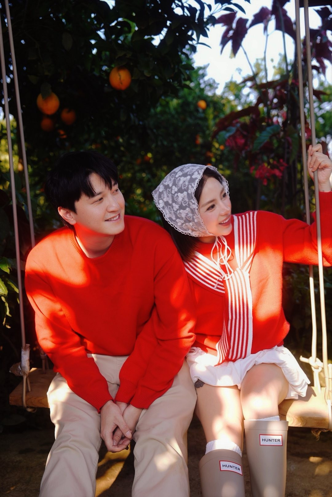 Cả hai cùng diện trang phục áo đỏ rực rỡ, tạo dáng tình tứ giữa không gian ngập tràn sắc đỏ cam.