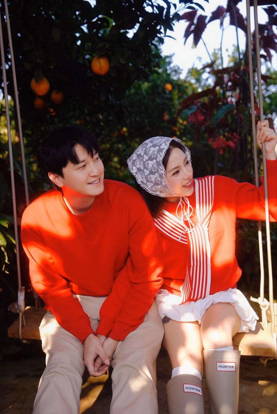 Cả hai cùng diện trang phục áo đỏ rực rỡ, tạo dáng tình tứ giữa không gian ngập tràn sắc đỏ cam.