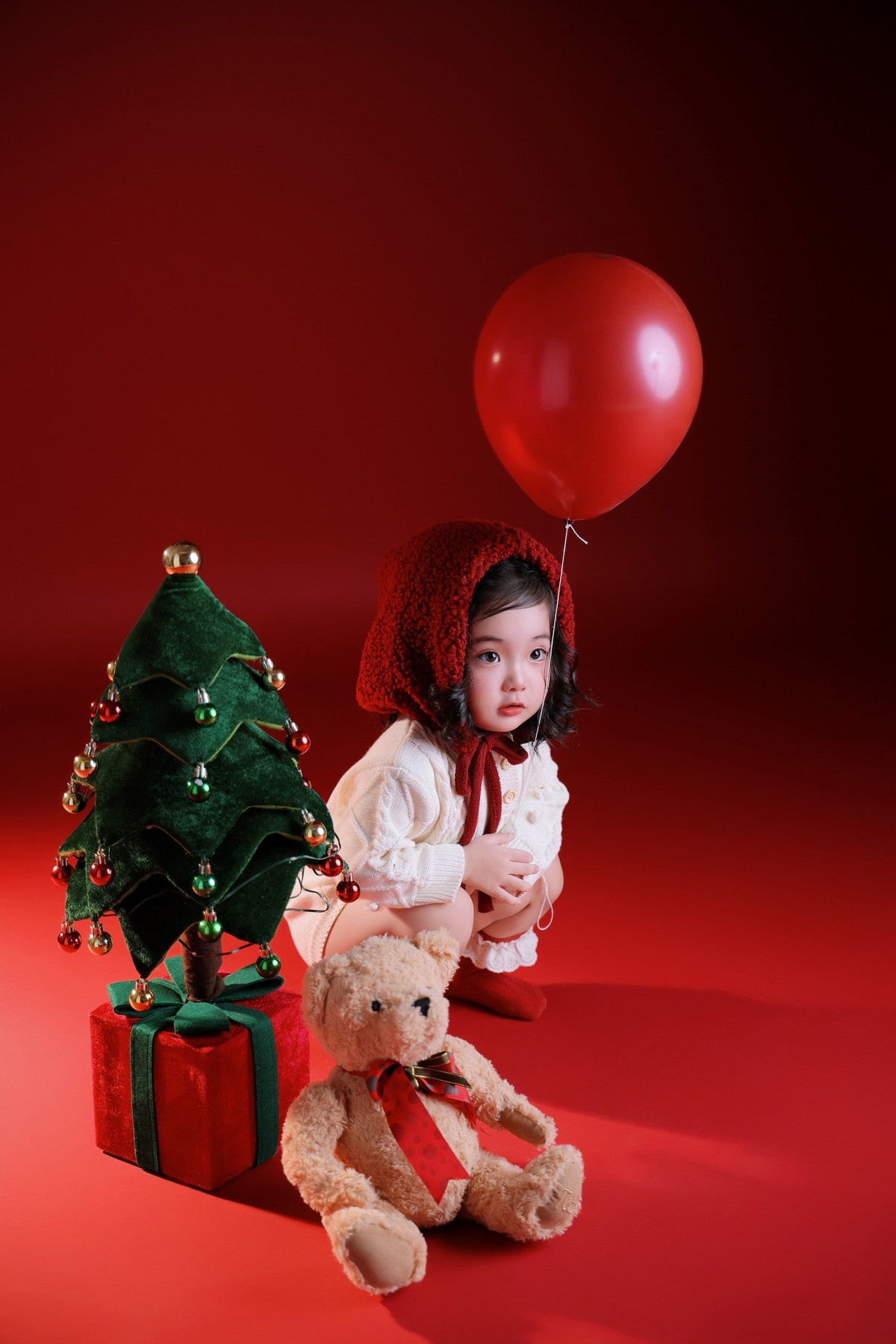 Từ khoảnh khắc ngồi ngoan ngoãn bên chú gấu bông, đứng cạnh cây thông nhỏ xinh cho đến lúc cười tươi nhìn thẳng vào ống kính, cô bé đều toát lên nét đáng yêu rất riêng.