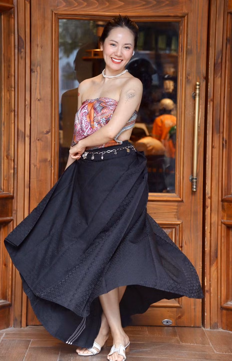 Cô kết hợp khăn làm áo với chân váy dài xòe màu đen, tạo nên tổng thể hài hòa giữa nét mềm mại, nữ tính và vẻ quyến rũ hiện đại.