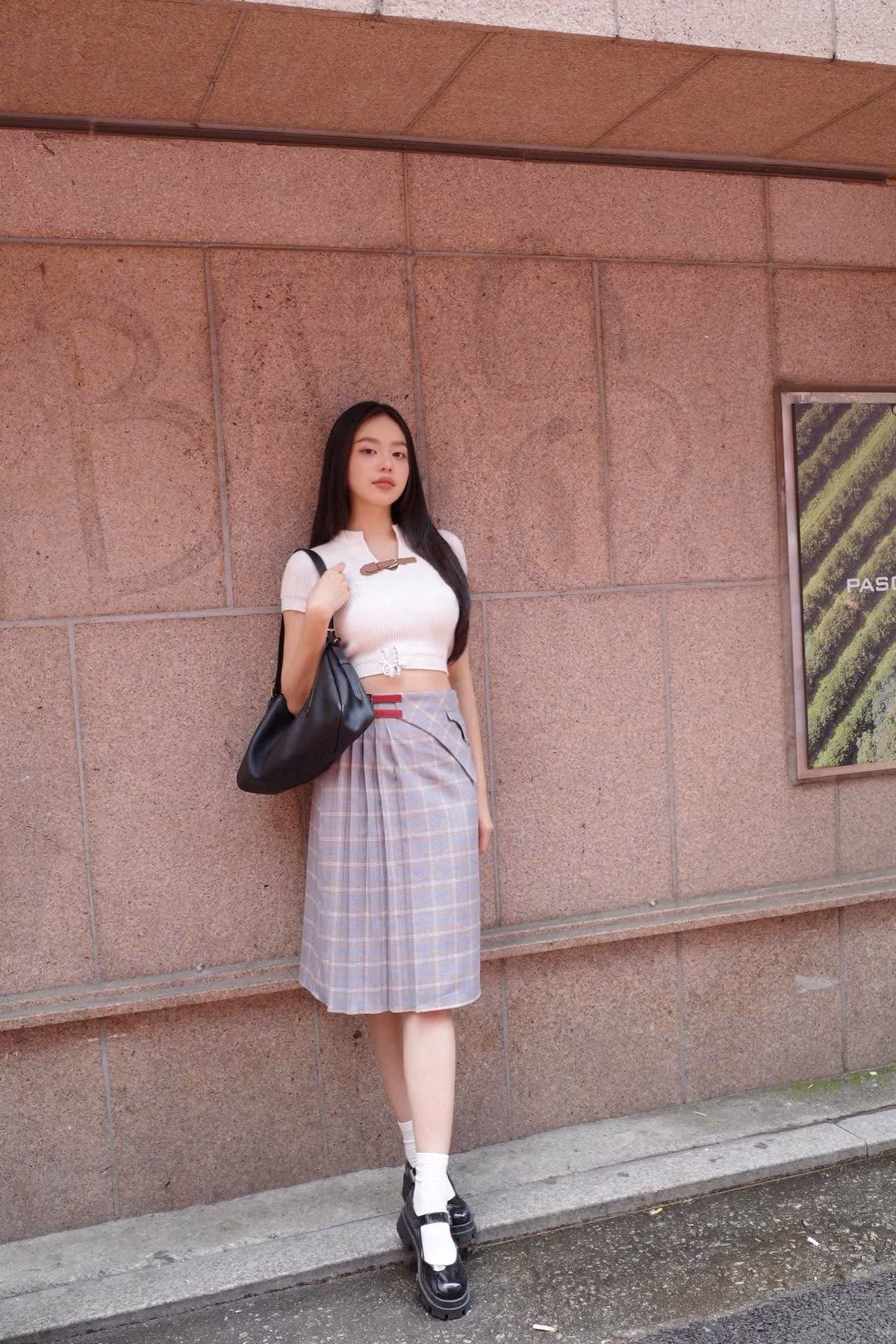 Điểm nhấn của outfit nằm ở chi tiết khoá da đồng điệu, tạo sự kết nối tinh tế giữa áo và váy.