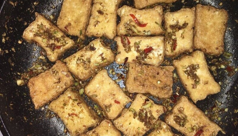 Không dừng lại ở các món kho truyền thống, đậu phụ còn có thể chế biến theo phong cách cay thơm với đậu phụ chiên sả ớt. Sau khi chiên giòn, đậu được đảo cùng sả băm và ớt phi thơm, tạo nên lớp vỏ ngoài giòn rụm nhưng bên trong vẫn mềm mịn.