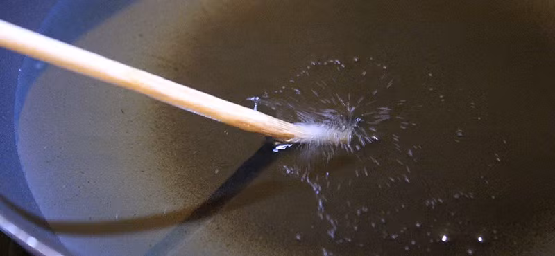 Dùng đũa gỗ để kiểm tra dầu sôi: Không cần nhiệt kế nhà bếp, chỉ cần một chiếc đũa gỗ. Đặt đầu đũa vào chảo dầu, nếu thấy bong bóng nhỏ li ti nổi lên quanh đầu đũa, nghĩa là dầu đã đủ nóng để chiên thực phẩm.