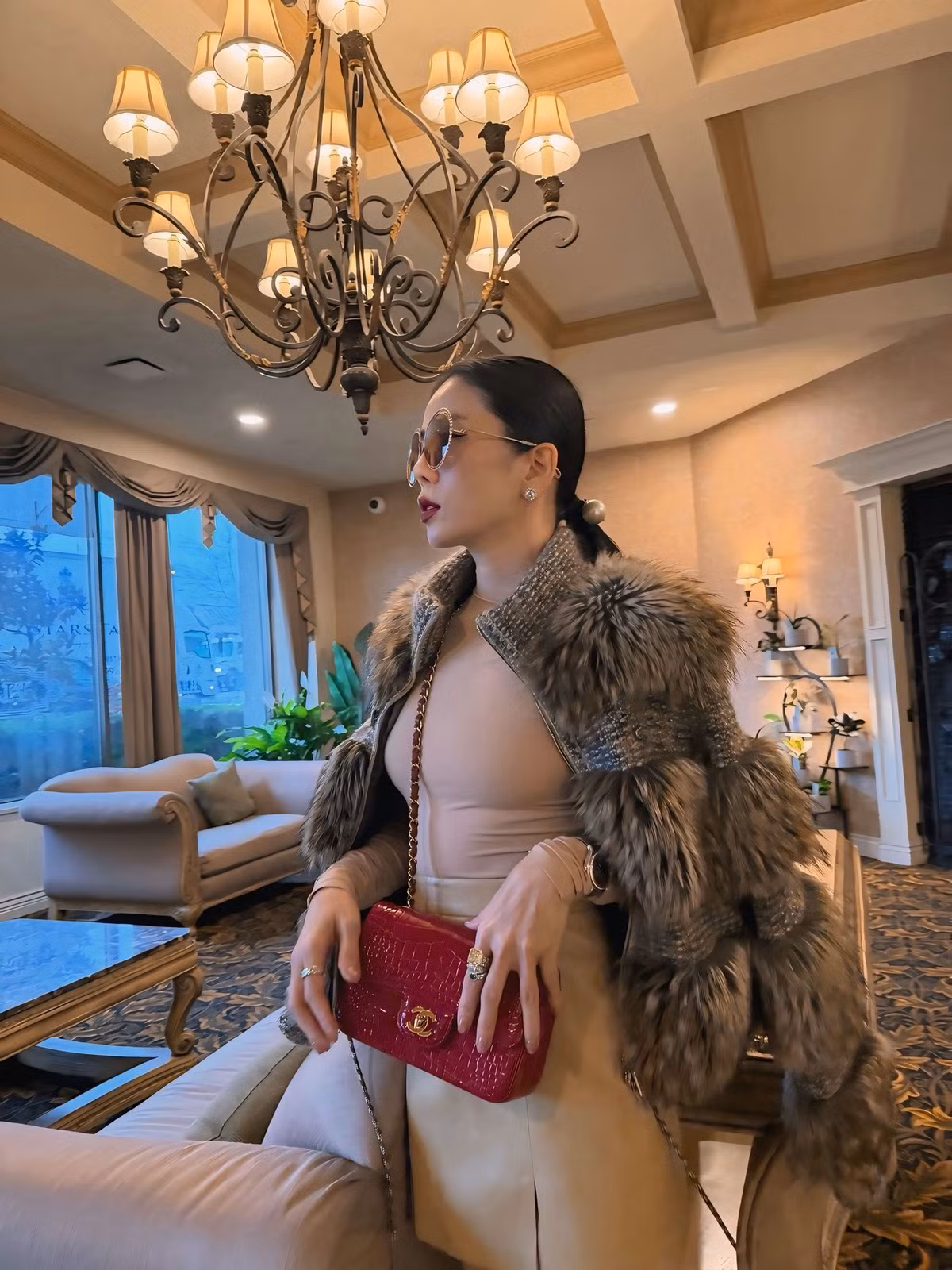 Đôi boots cao mang lại vẻ cá tính hiện đại, trong khi chiếc áo khoác lông thời thượng cùng túi xách đỏ nổi bật tạo nên điểm nhấn sang chảnh trong outfit của Lệ Quyên giữa không gian khách sạn mang phong cách châu Âu.