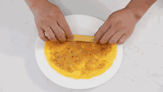 Bước 5: Trải trứng tráng lên thớt cho nguội rồi cho hỗn hợp tôm, cà rốt và trứng trải dàn đều lên lớp trứng tráng đó. Cuối cùng, bạn cuộn trứng lại.