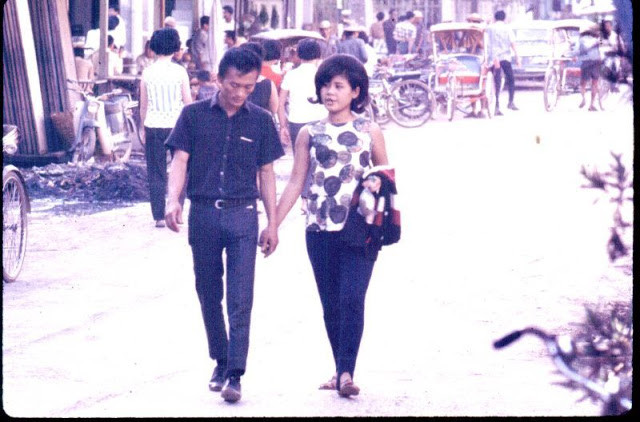 Cặp đôi tay trong tay đi trên con phố sầm uất.