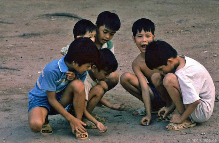 Các cậu bé chơi bắn bi trên một đoạn vỉa hè trải bê tông ở bờ hồ, 1992.