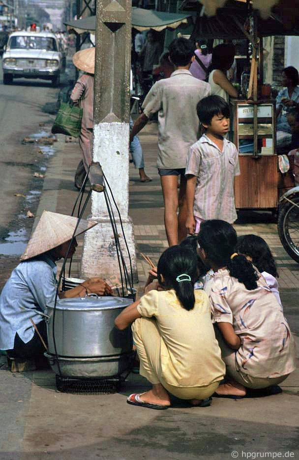 Phụ nữ và trẻ em ngồi xổm ngay trên lòng đường để ăn quà vặt.