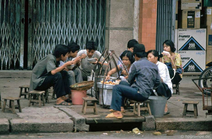 Khách hàng thoải mái thưởng thức đồ ăn đường phố ngay trên nắp cống.