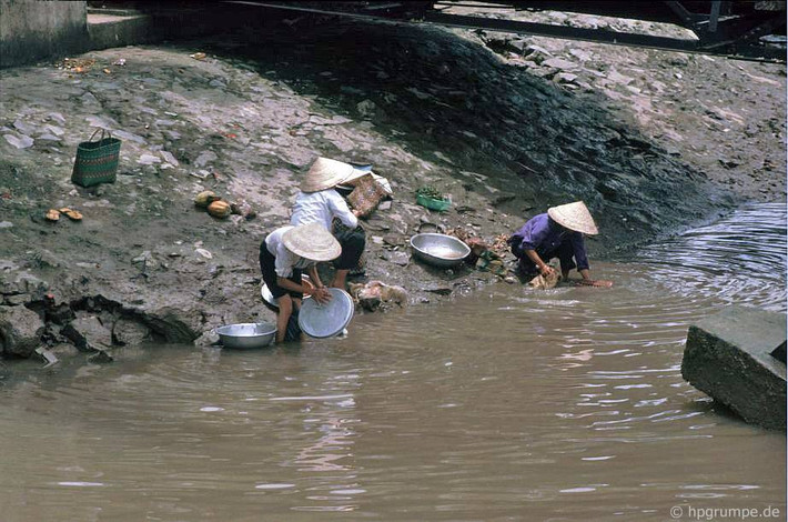 Những người bán rong rửa đồ nghề ở bờ sông.