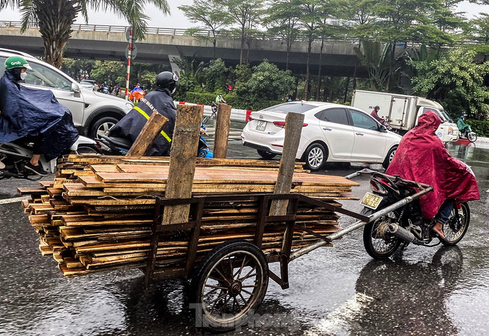 Ghi nhận sáng 1/12, dù trời mưa tầm tã, các phương tiện chở hàng cồng kềnh vẫn xuất hiện rất nhiều trên đường phố Hà Nội. Đường trơn trượt, đầu và cuối xe không có vật liệu che chắn, cảnh báo cho người đi đường.