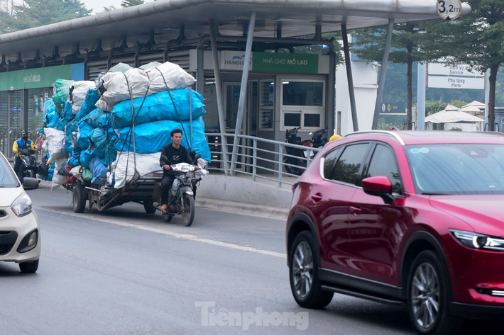Một người đàn ông chở cả núi rác trên xe, không đội mũ bảo hiểm lưu thông trên đường Tố Hữu.