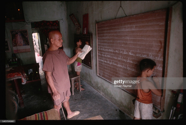 Cụ ông kèm cặp hai đứa cháu nhỏ học hành tại nhà mình ở Hội An, 1993.